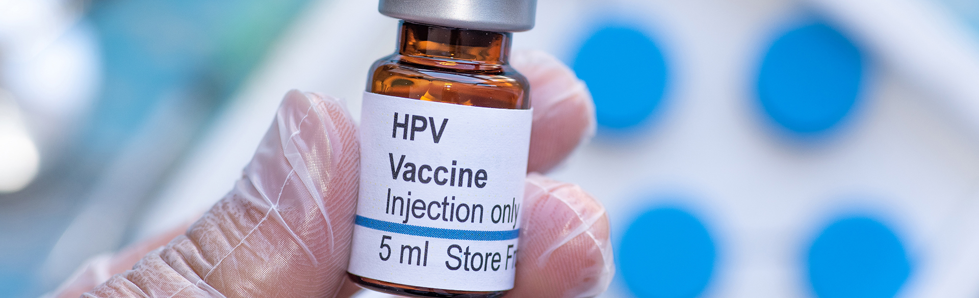 Hand holding a bottle of liquid HPV vaccine