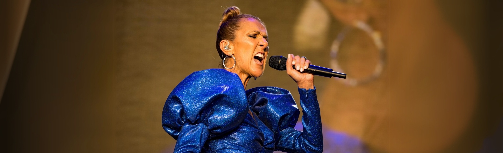 Celine Dion singing on state in bright blue dress with microphone