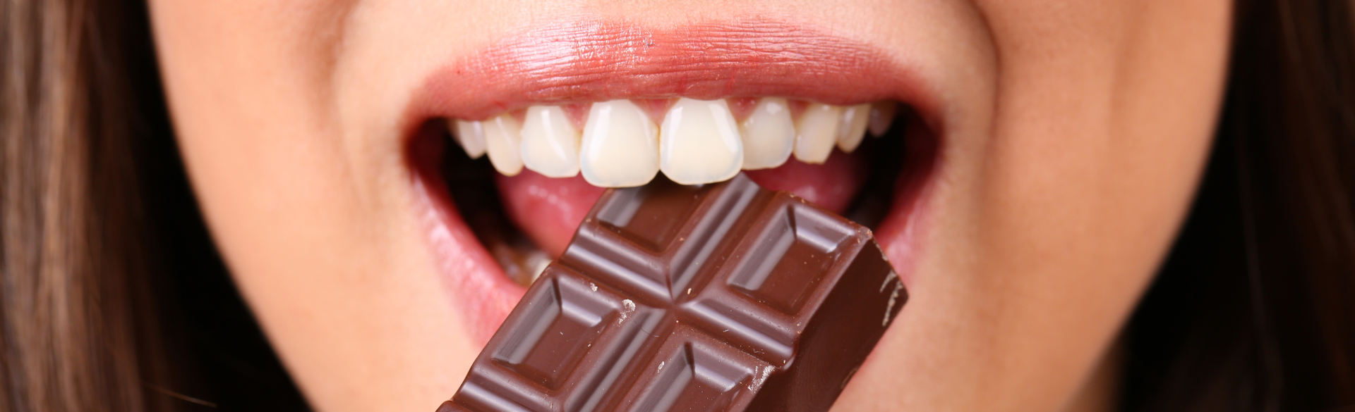 woman with nice teeth biting chocolate bar 