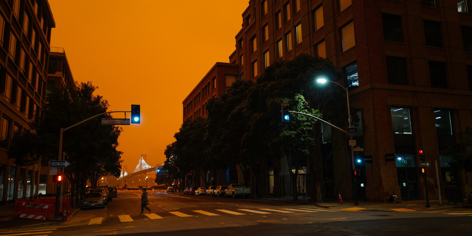 A view of a city street intersection with skies made orange from forest fires. 