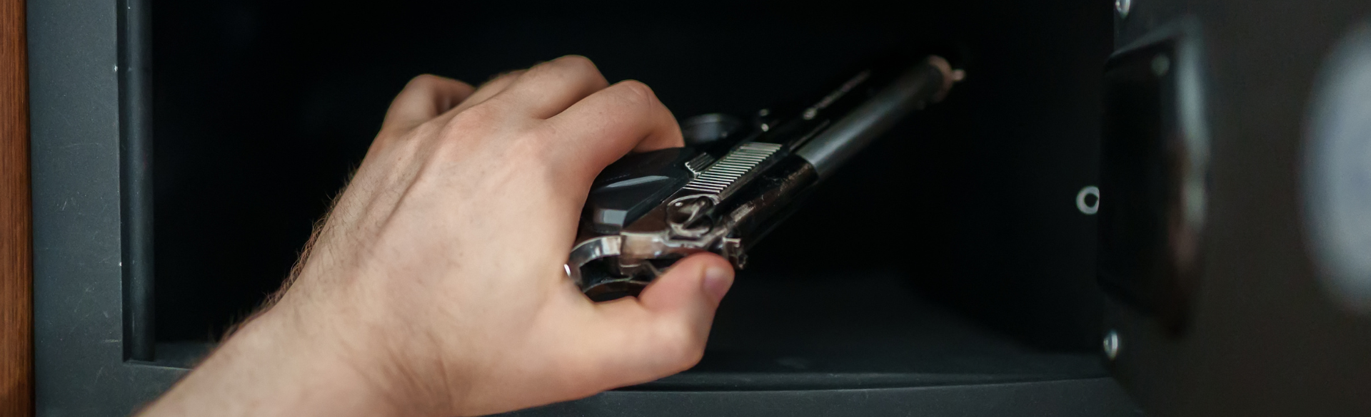 Hand holding a revolver, placing it in a lock box for storage