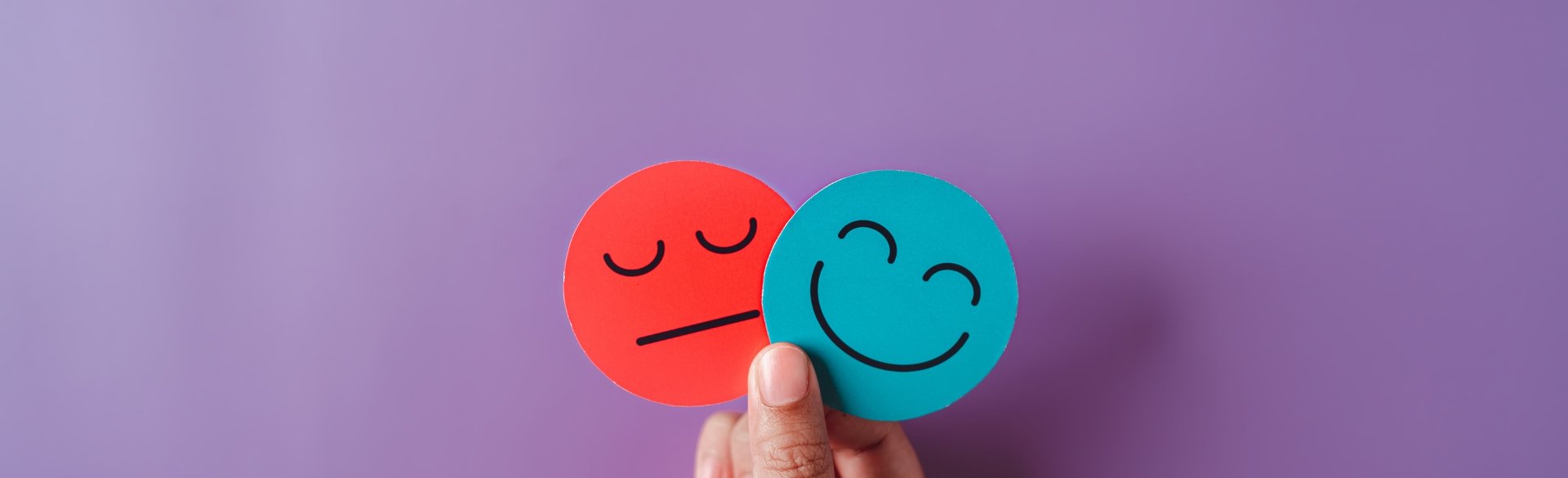Person holding happy and sad faces