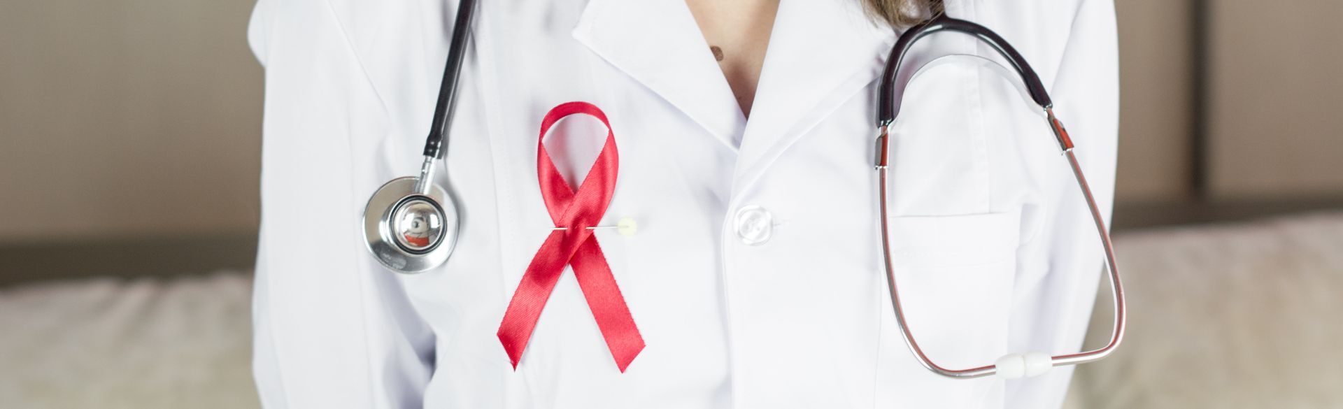 Doctor with stethoscope and cancer ribbon pinned to white coat