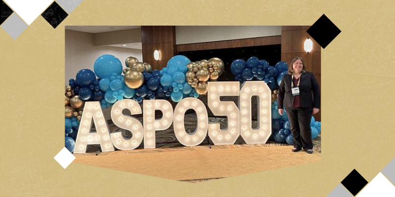 Erin Hirsch in front of ASPO50 light up sign with blue and yellow balloon garland around it