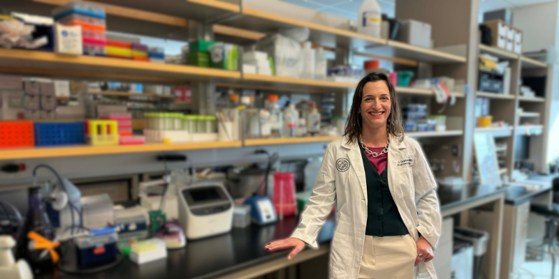 Doctor in her lab wearing a white coat with a black cardigan underneath | University of Colorado Anschutz Cancer Center