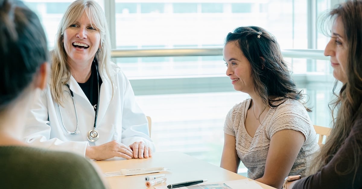 Woman with Down syndrome speaking with a doctor at a table