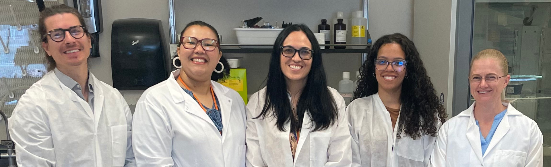 Maria Amaya, MD, PhD, pictured center, smiles alongside fellow researchers in her lab, the Amaya Lab.