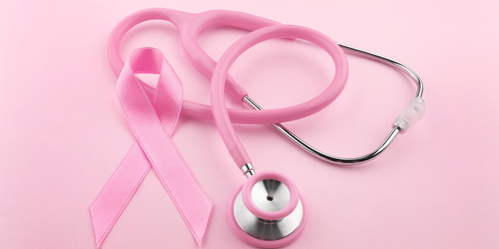 A pink stethoscope lying beside a pink ribbon.