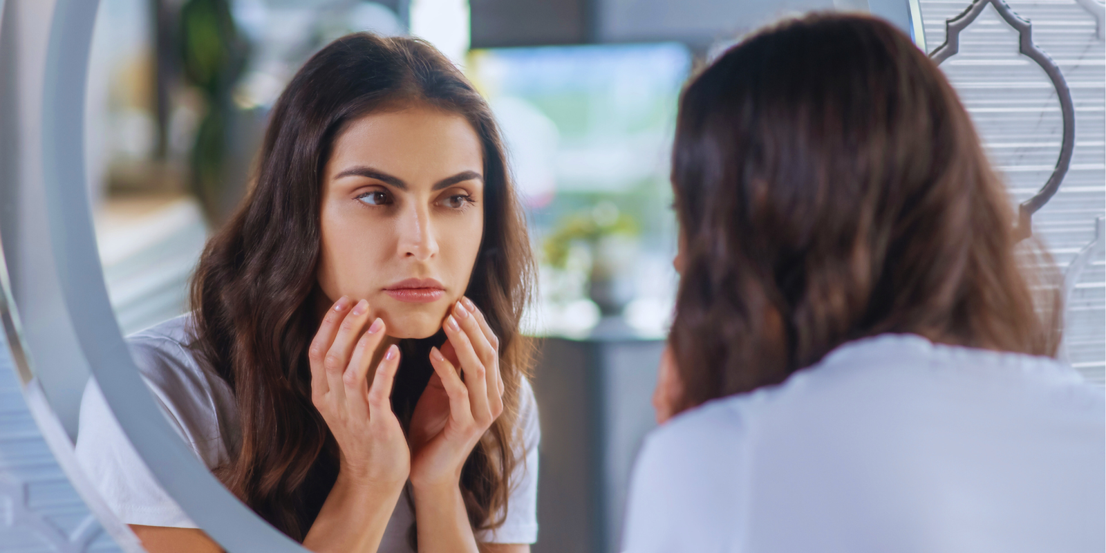 Woman looking at her face in the mirror.