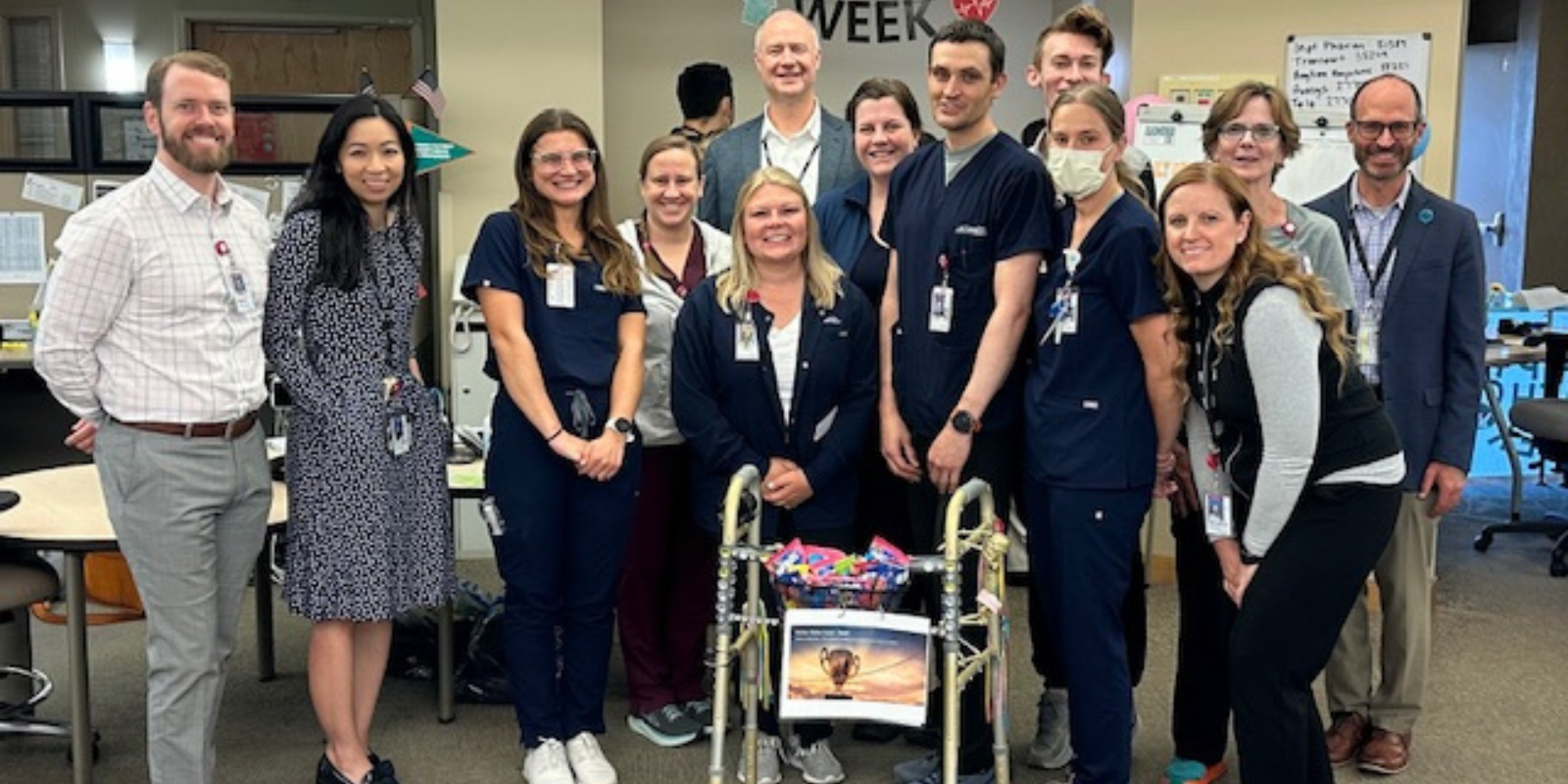 Group of health care providers smile behind a golden walker.