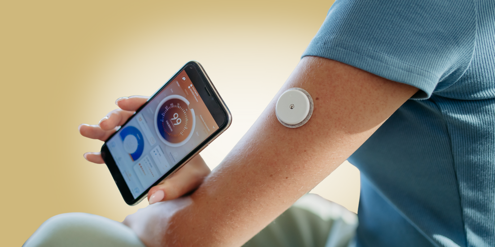 A woman wears a continuous glucose monitor that connects to a smartphone app.