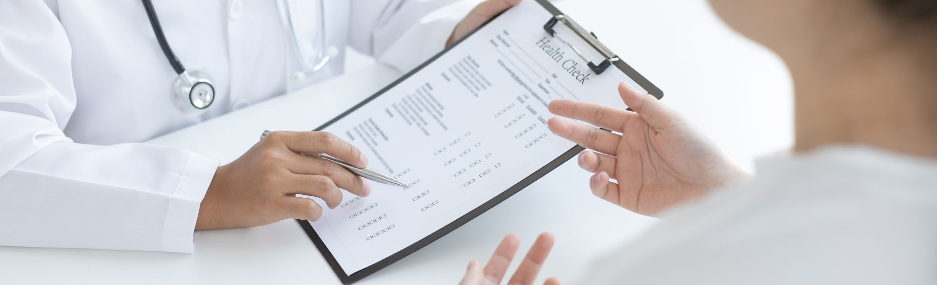 A doctor holding a chart while talking with a patient.