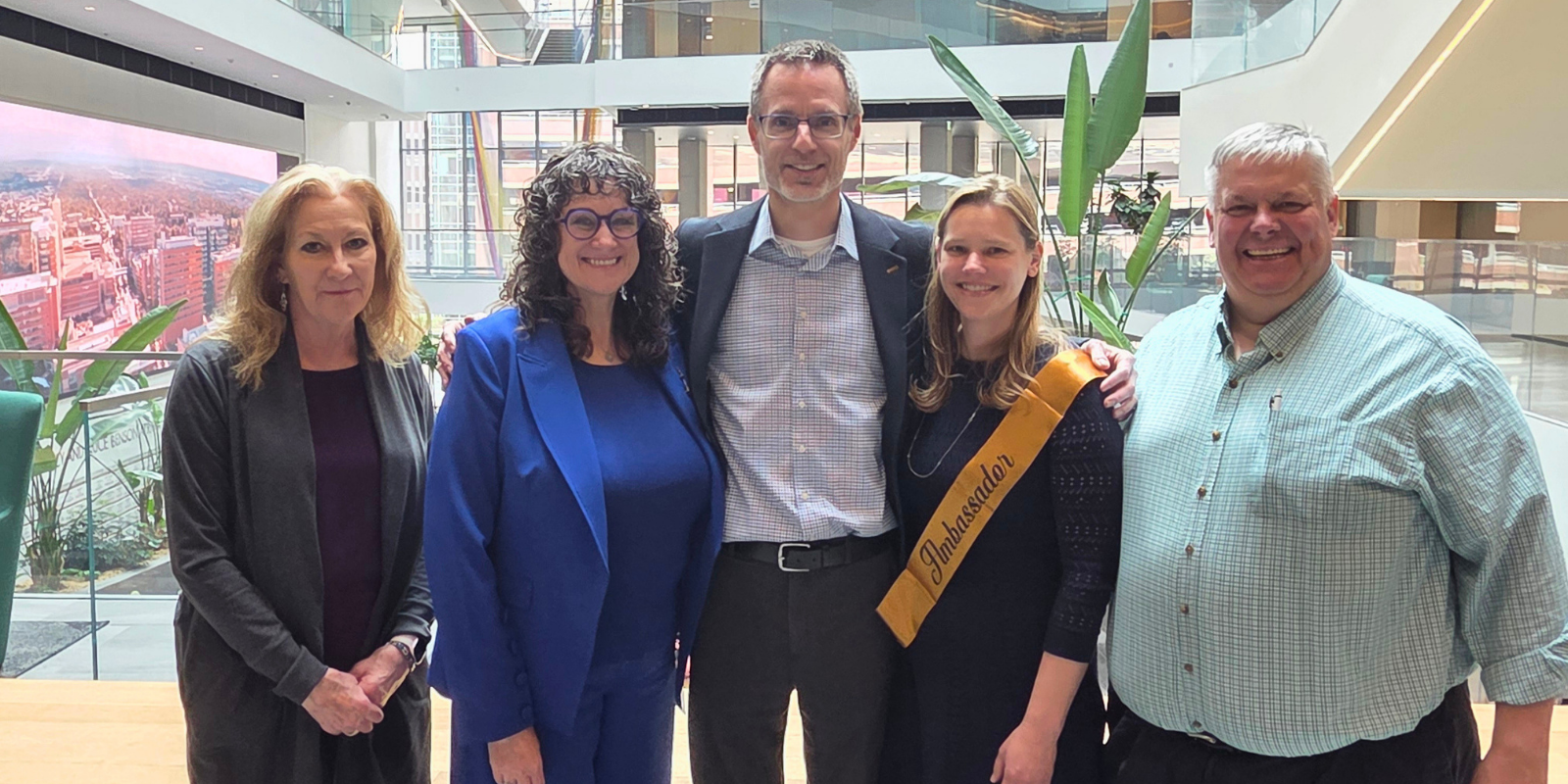 Five adults smile together at the CU Anschutz campus.