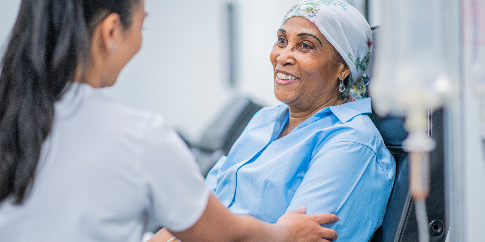 A cancer patient smiles while speaking with a health care provider.