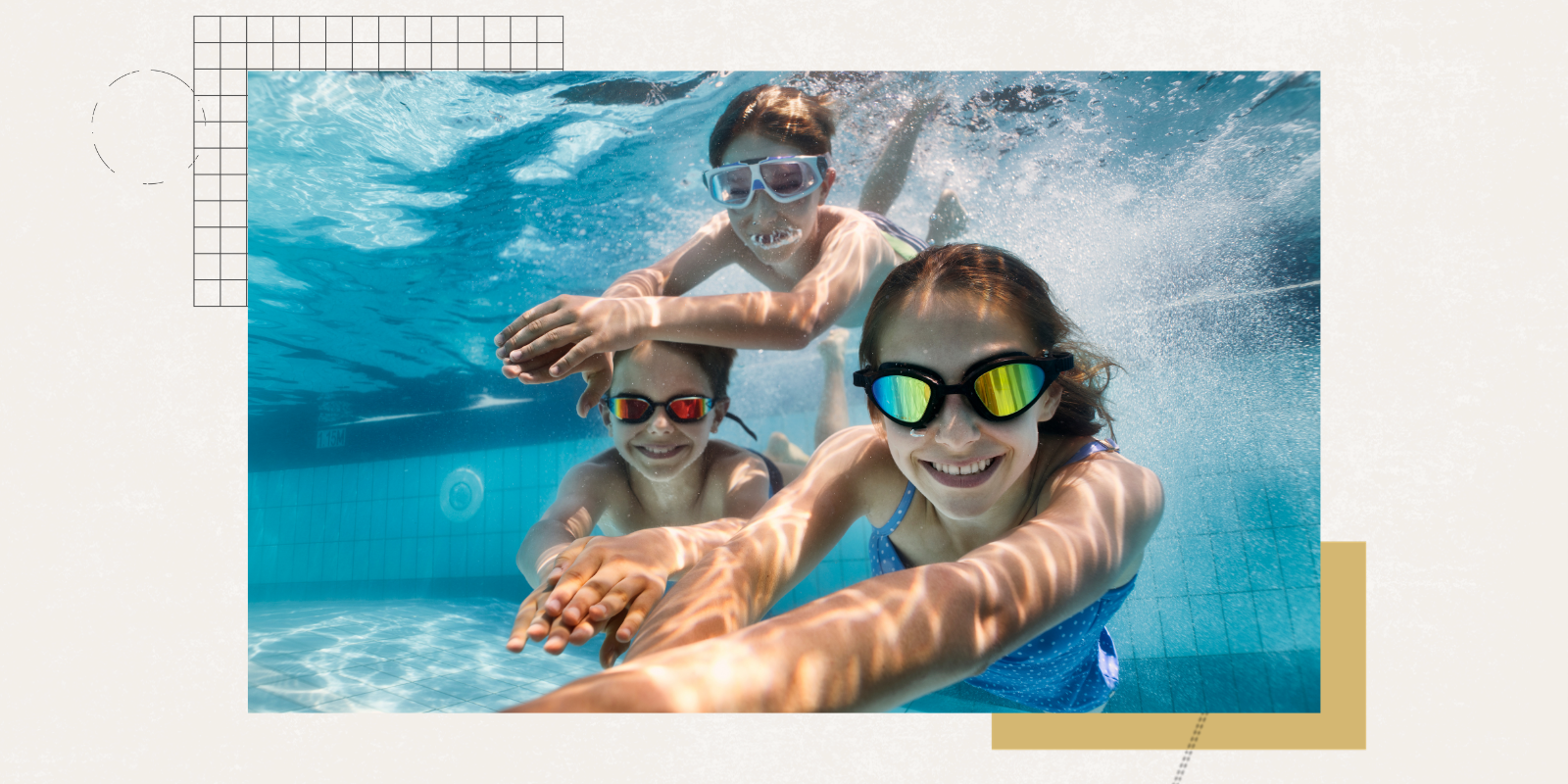 Three kids swim underwater while wearing goggles.