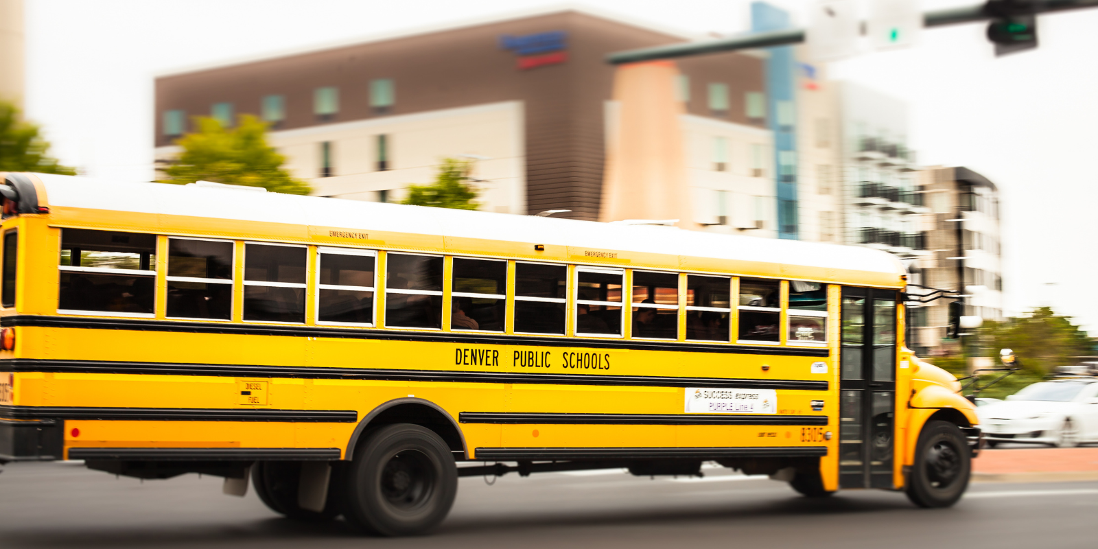 A Denver school bus driving down the street.
