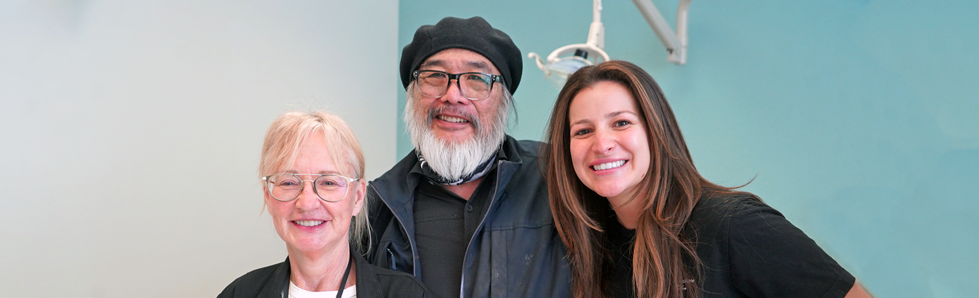 three people smiling at the camera in a dental clinic