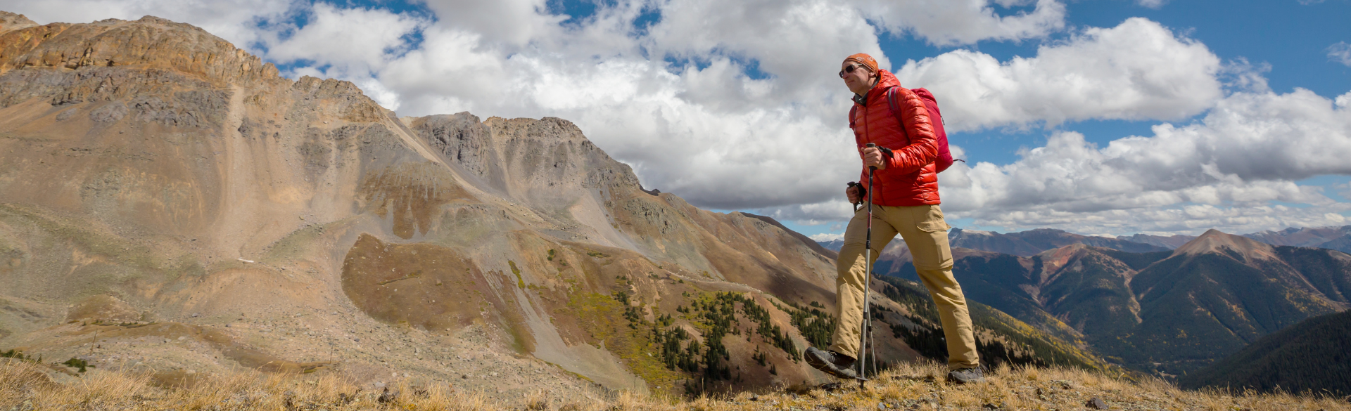 Man hikes a mountain on a partially cloudy day