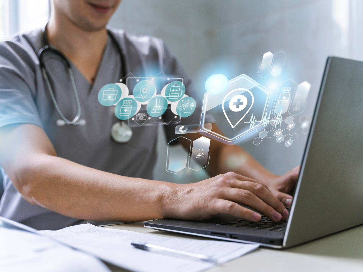 Medical professional typing on a computer with digital icons overlayed onto the foreground