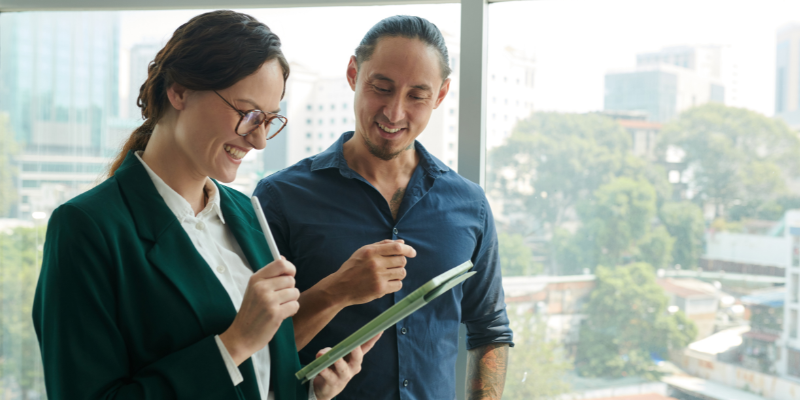 Two people smiling and looking at Ipad.
