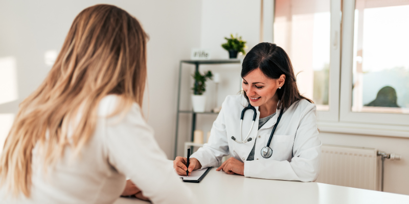 Dr. and patient at a table looking at paperwork and smiling.