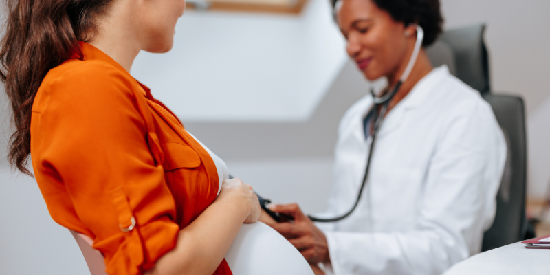 Dr. listening to a pregnant woman's belly.