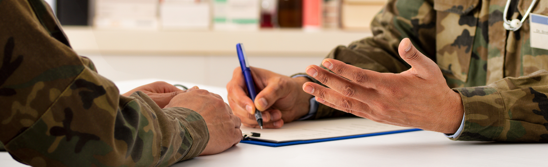 A person in a military uniform writes on a medical chart.