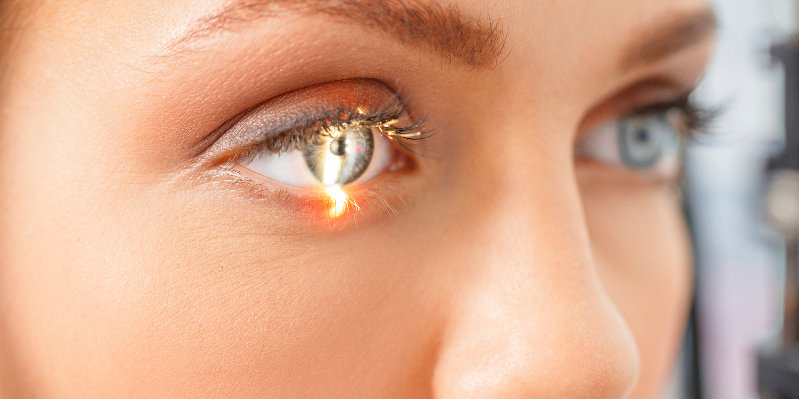 A close-up image of a woman's eye with light reflecting from an ophthalmic exam. 