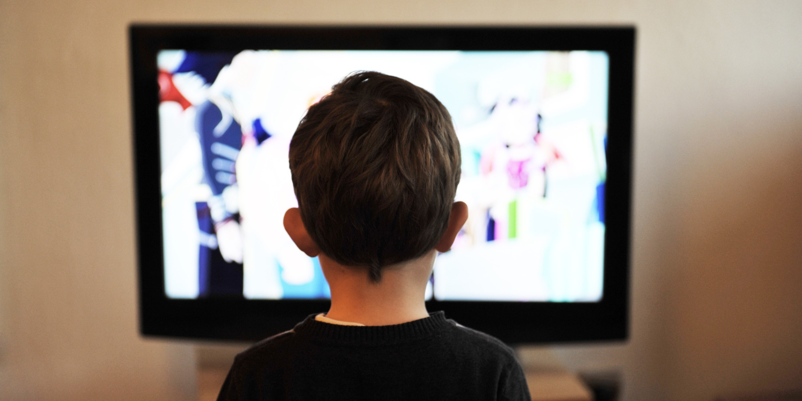 Young boy sits in front of a television 