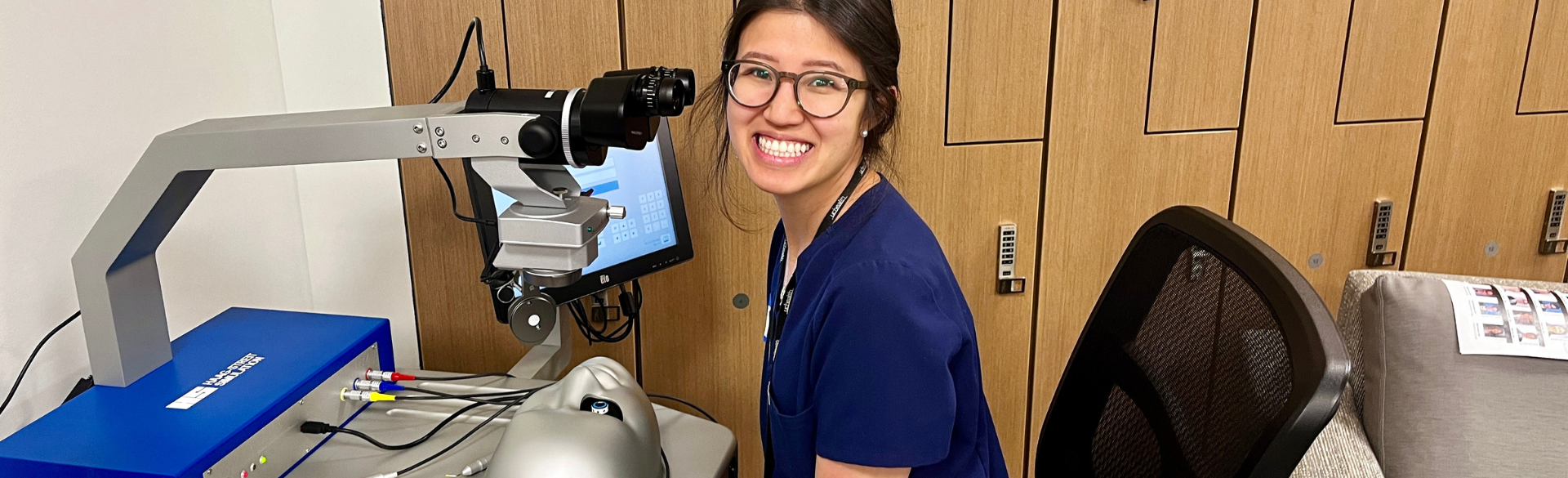 Ophthalmology residents smiles for a photo while using the surgery simulator 