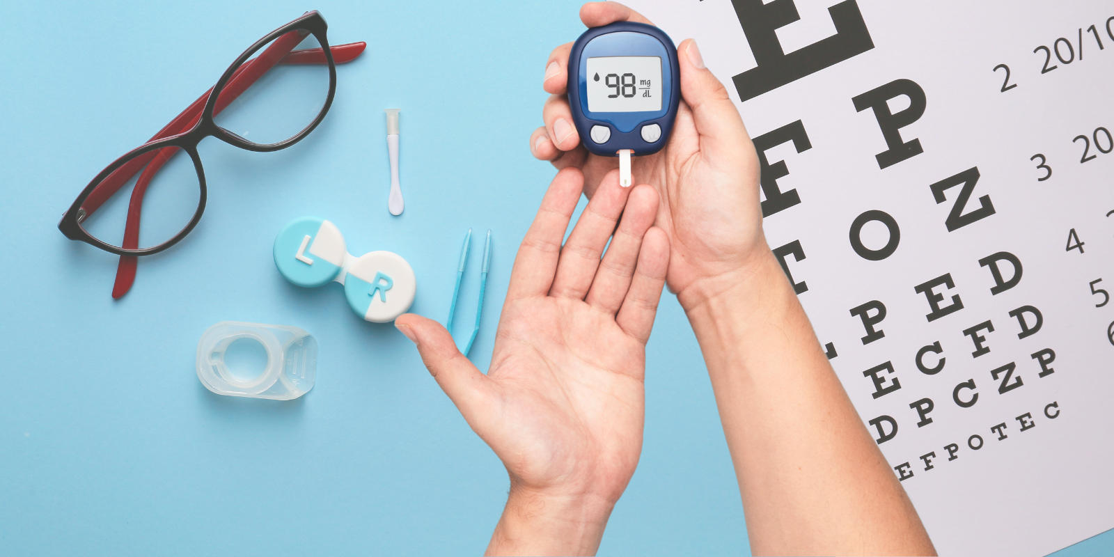 Close up of a glucose monitor and a hand with a background of ophthalmology equipment, including glasses and contacts.