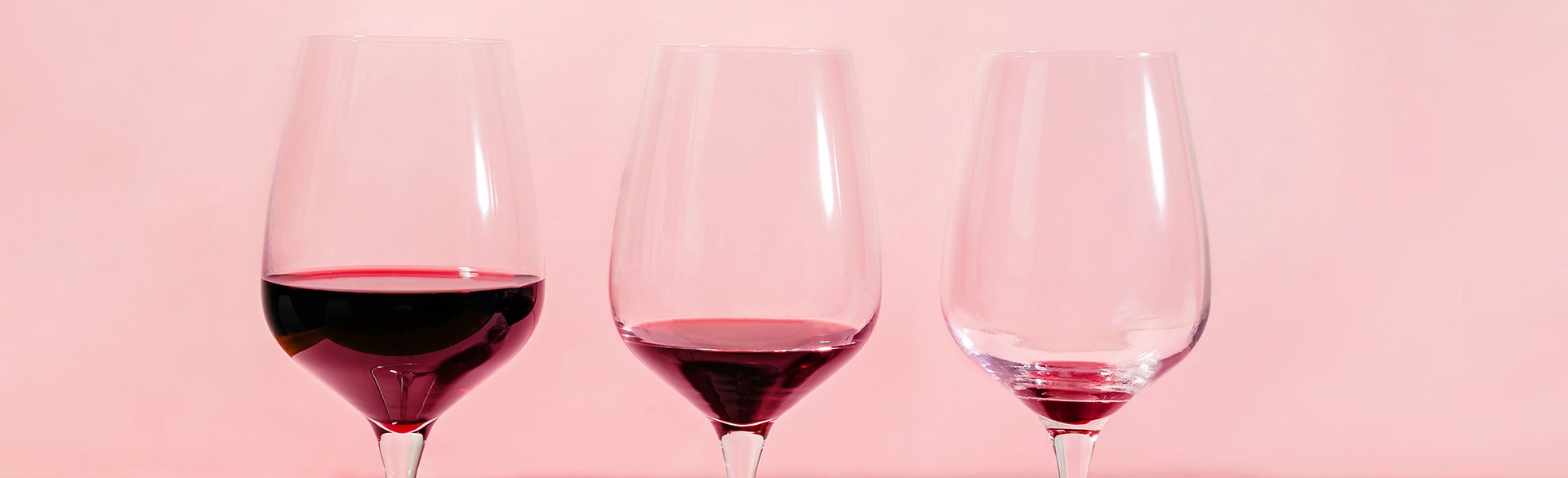 Three wine glasses with decreasing volumes of red wine