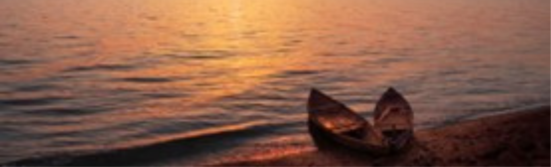 Two canoes sitting in the water at sunset. 