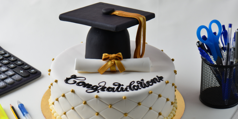Image of a graduation cake with the word "congratulations" surrounded by miscellaneous office desk things