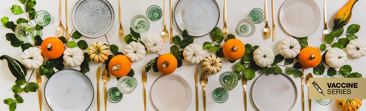 A set table with orange and white mini pumpkins