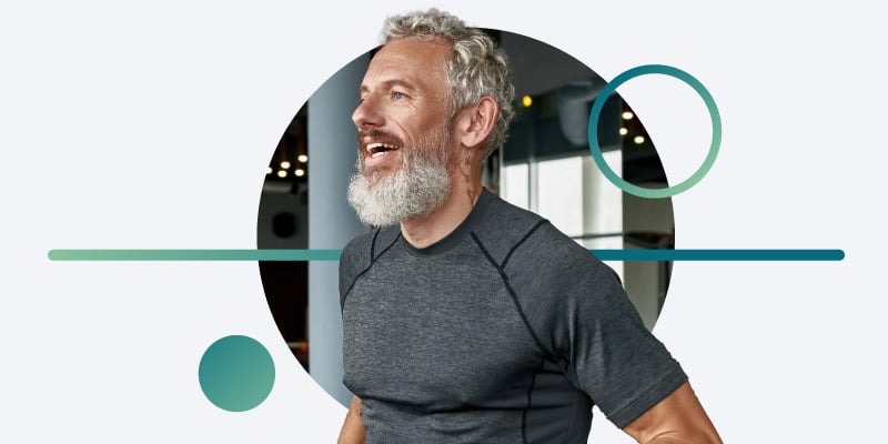 Active senior man jogging on treadmill in sports center with teal graphics