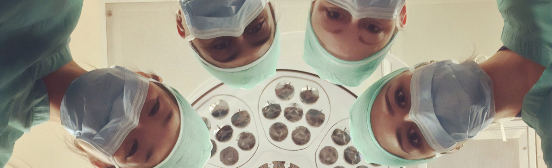 People wearing surgical gear looking down on operating table