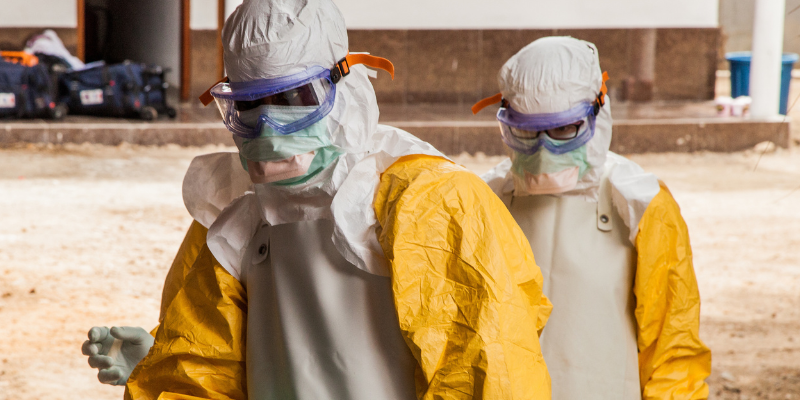 Medical cleaners in streets of Africa cleaning wearing hazmat suits
