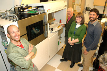 Researchers stand next to new 3D metal prototype machine