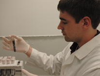 Carter Reid, a professional research assistant in Medical Oncology, examines a specimen in the lab