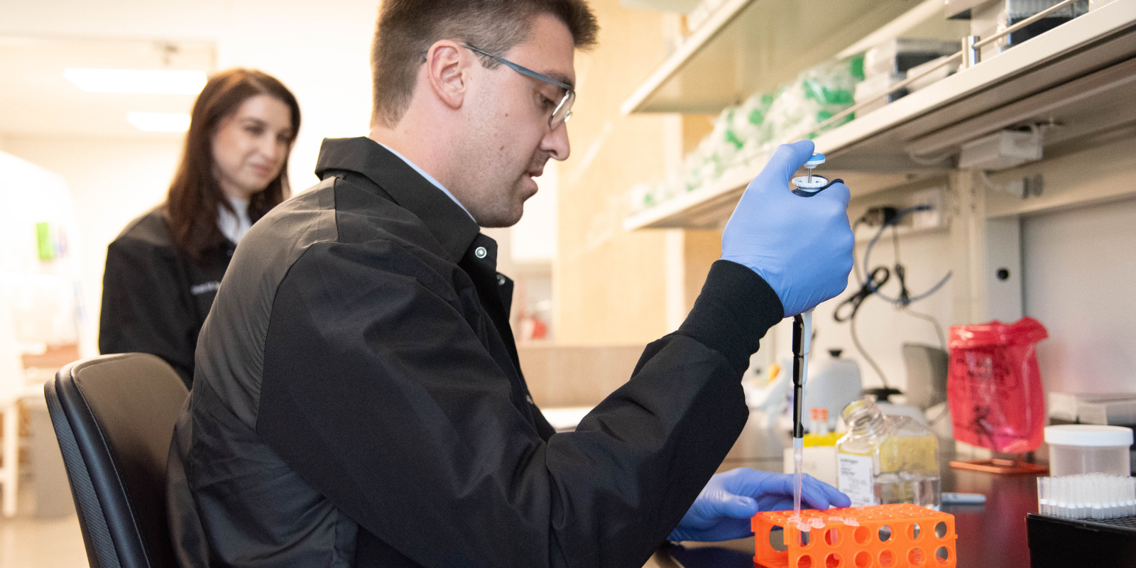 A man wearing gloves does work with a syringe in a laboratory.