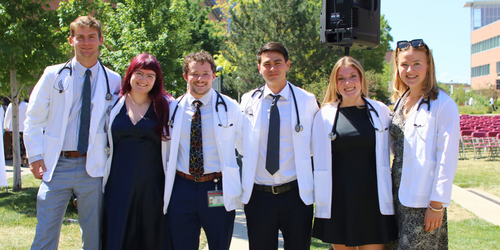 Six first-year medical students smile while wearing their white coats at CU Anschutz.