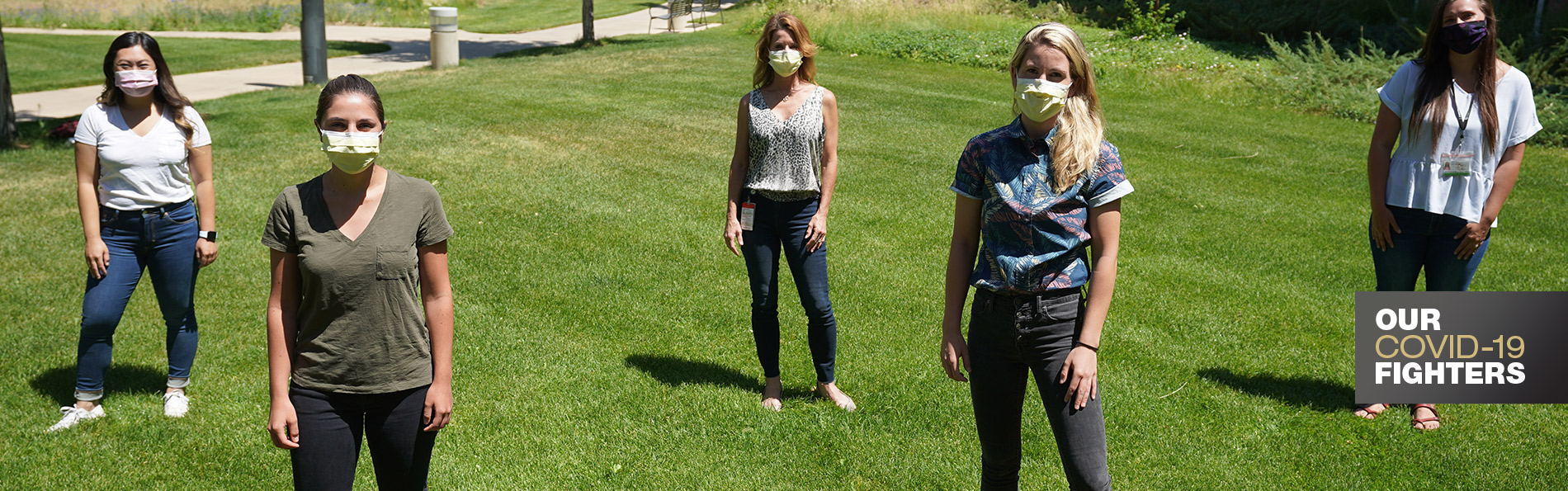 Students pose in masks on green lawn
