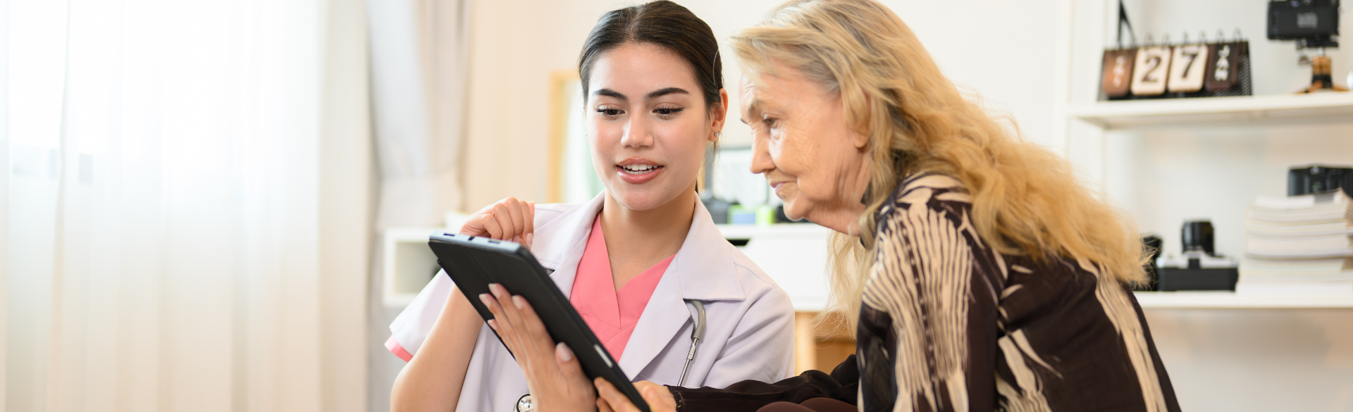 nurse and elderly woman looking at tablet