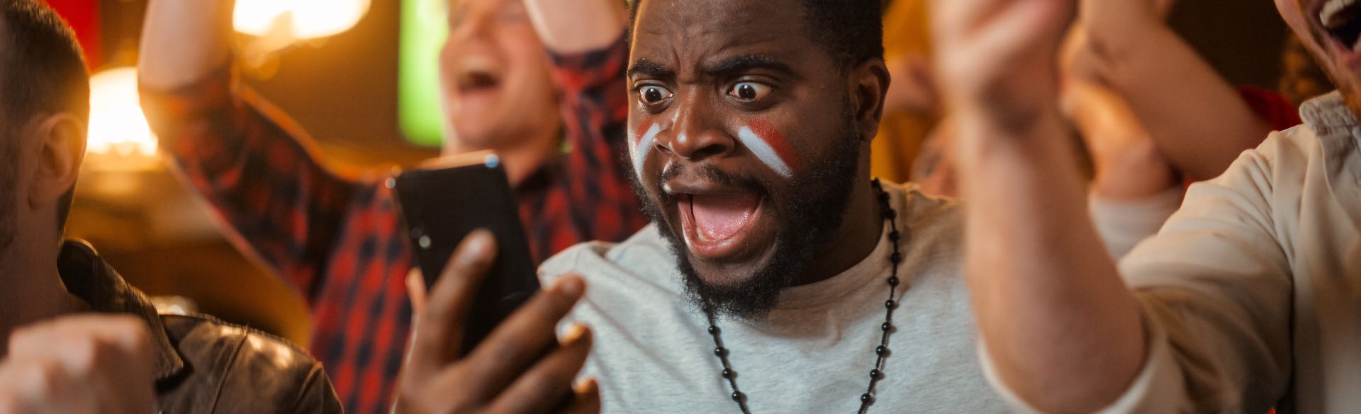 A fan sporting paint on his face expresses wide-eyed disbelief at what he sees on his phone