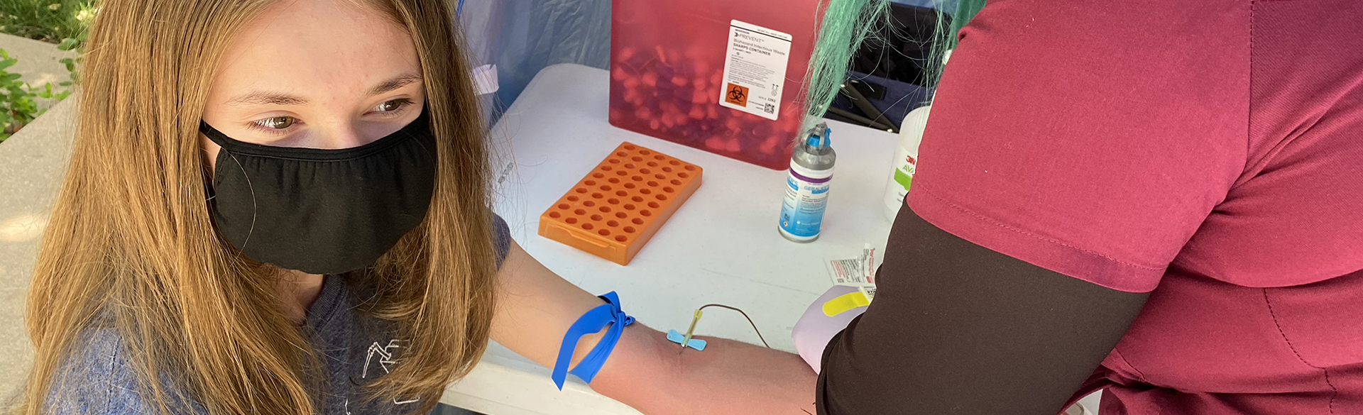 A young girl has blood drawn at an ASK station