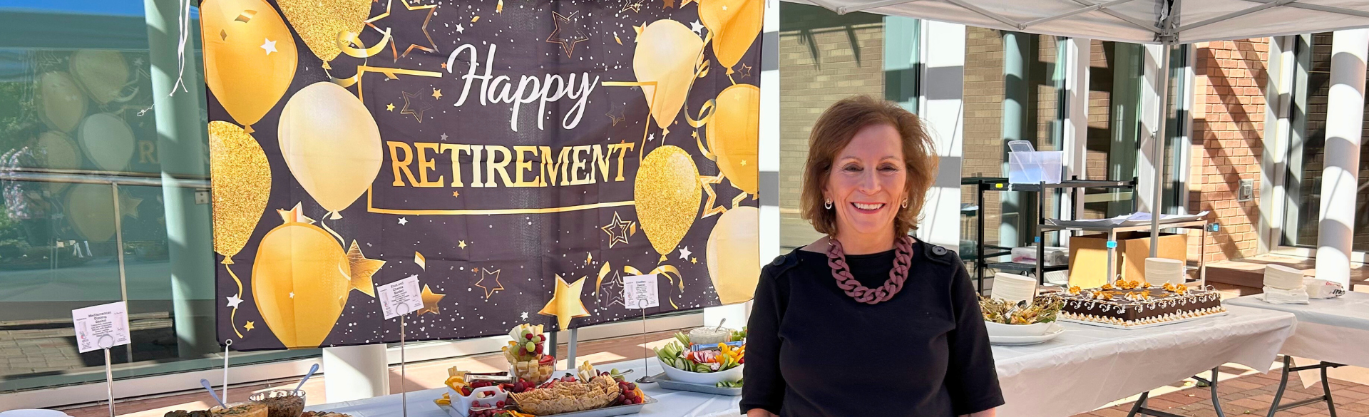 Terri Tilliss in front of a Happy Retirement banner