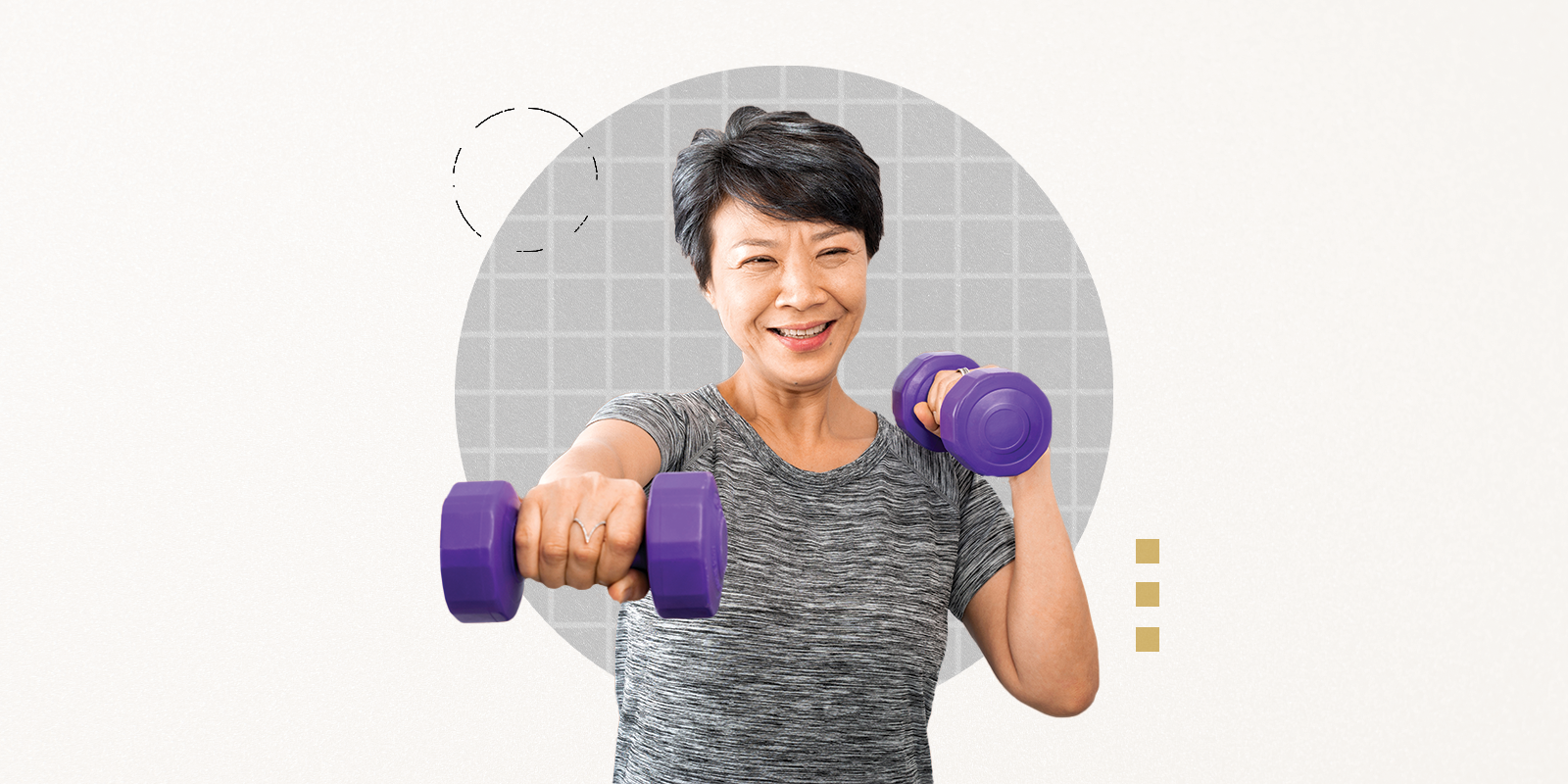 A smiling woman in a gray T-shirt with short, gray-streaked dark hair poses for the camera holding up purple dumbbells