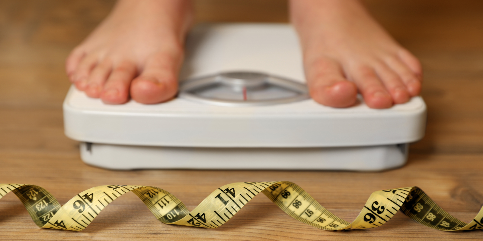 overweight girl on scale with measuring tape in front of it