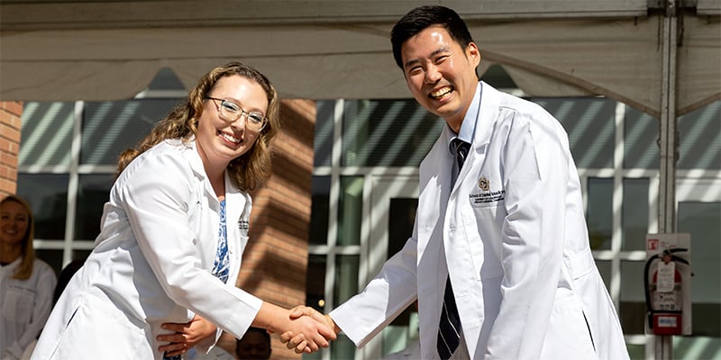 Student and faculty member shaking hands at ceremony